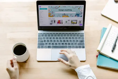 from_above_of_crop_anonymous_person_with_cup_of_black_coffee_using_laptop_while_sitting_at_table_with_opened_notebook_in_daylight.webp