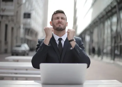 man_in_black_suit_sitting_on_chair_beside_buildings.webp