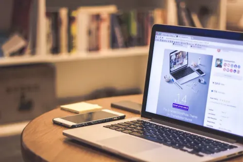 silver_laptop_computer_beside_white_smartphone_on_brown_wooden_table.webp