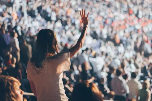 woman_with_white_shirt_raising_her_right_hand.webp